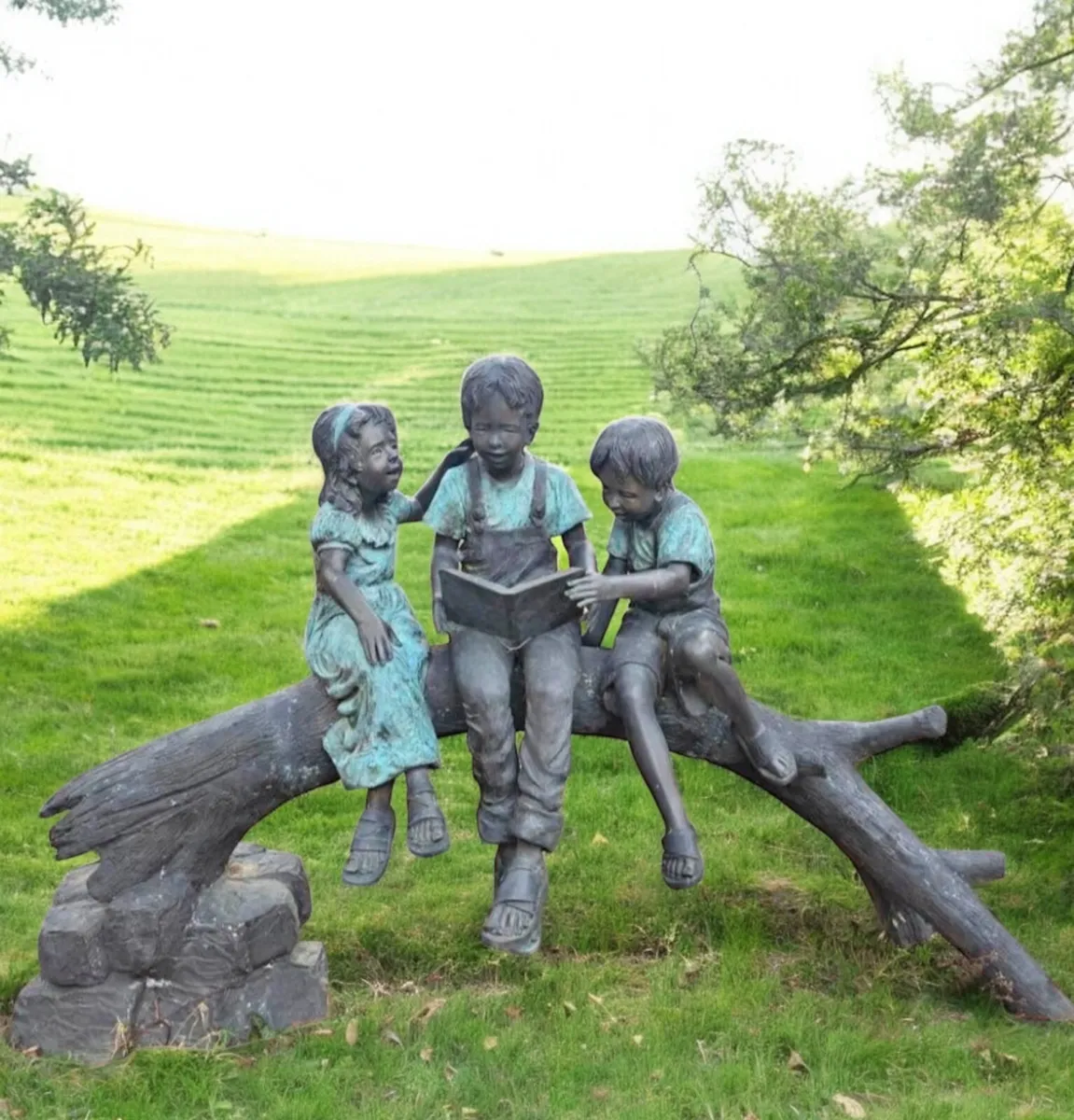 Bronze kids reading on log - Image 1