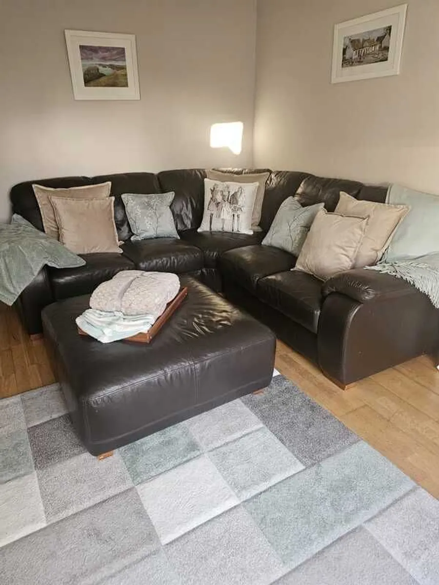 Leather L-shaped sofa with matching large square pouff.