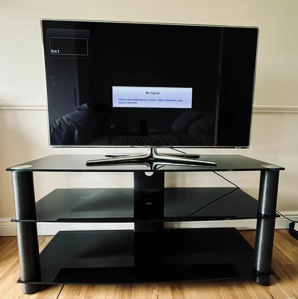 Samsung TV and black glass TV stand - Image 1
