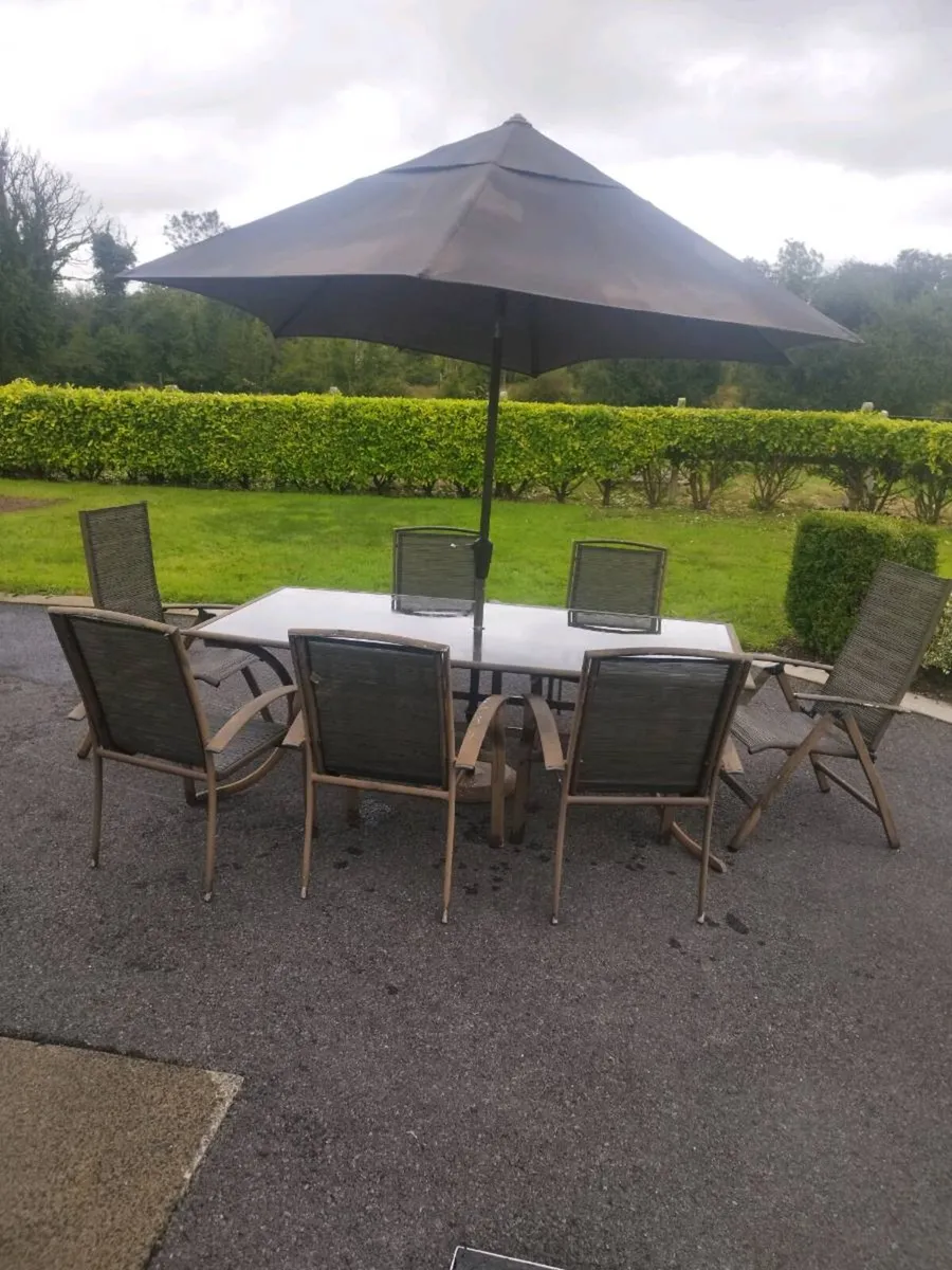 Outdoor table and chairs and umbrella. - Image 1