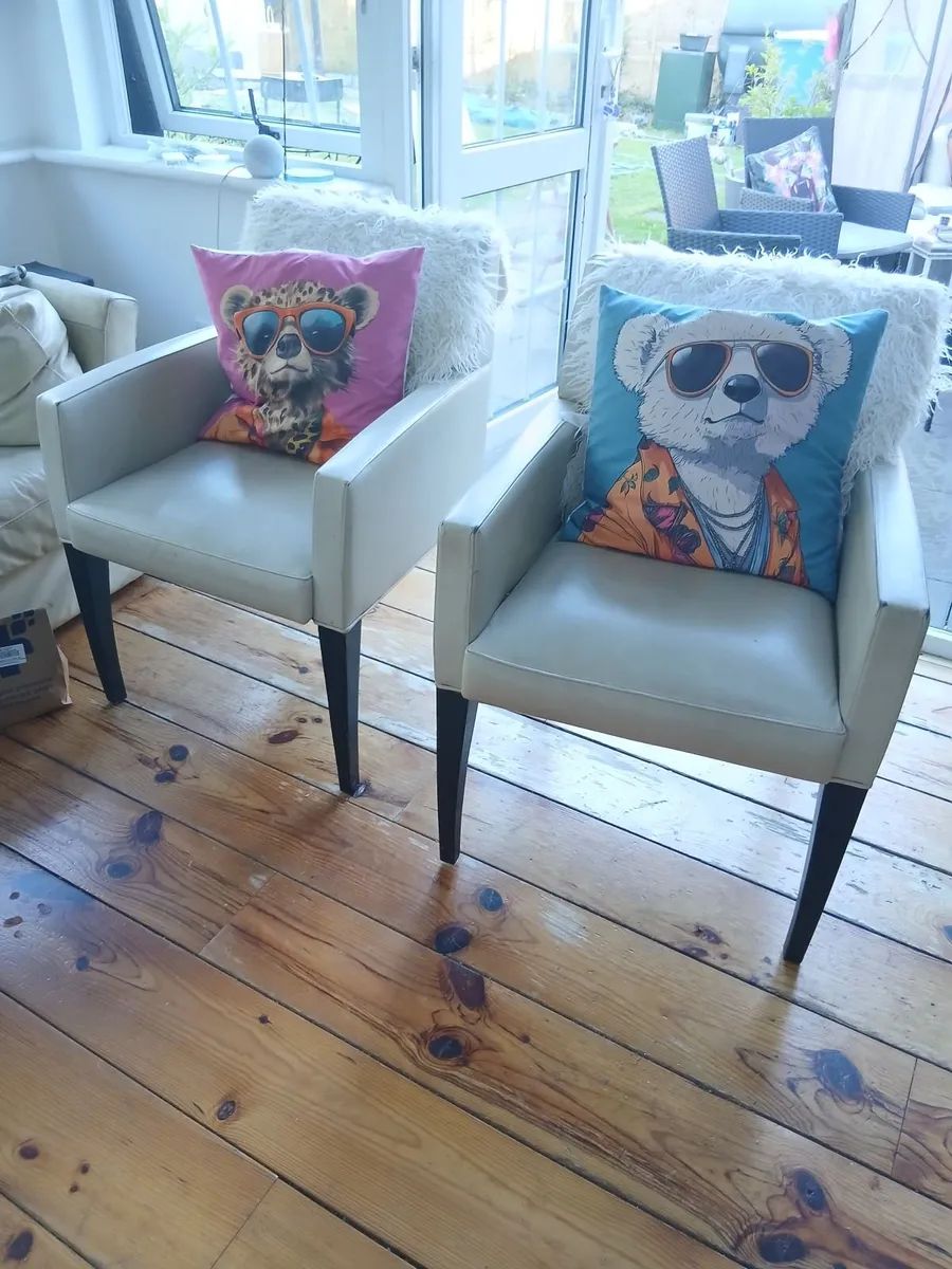 2 Cream leather effect chairs.
