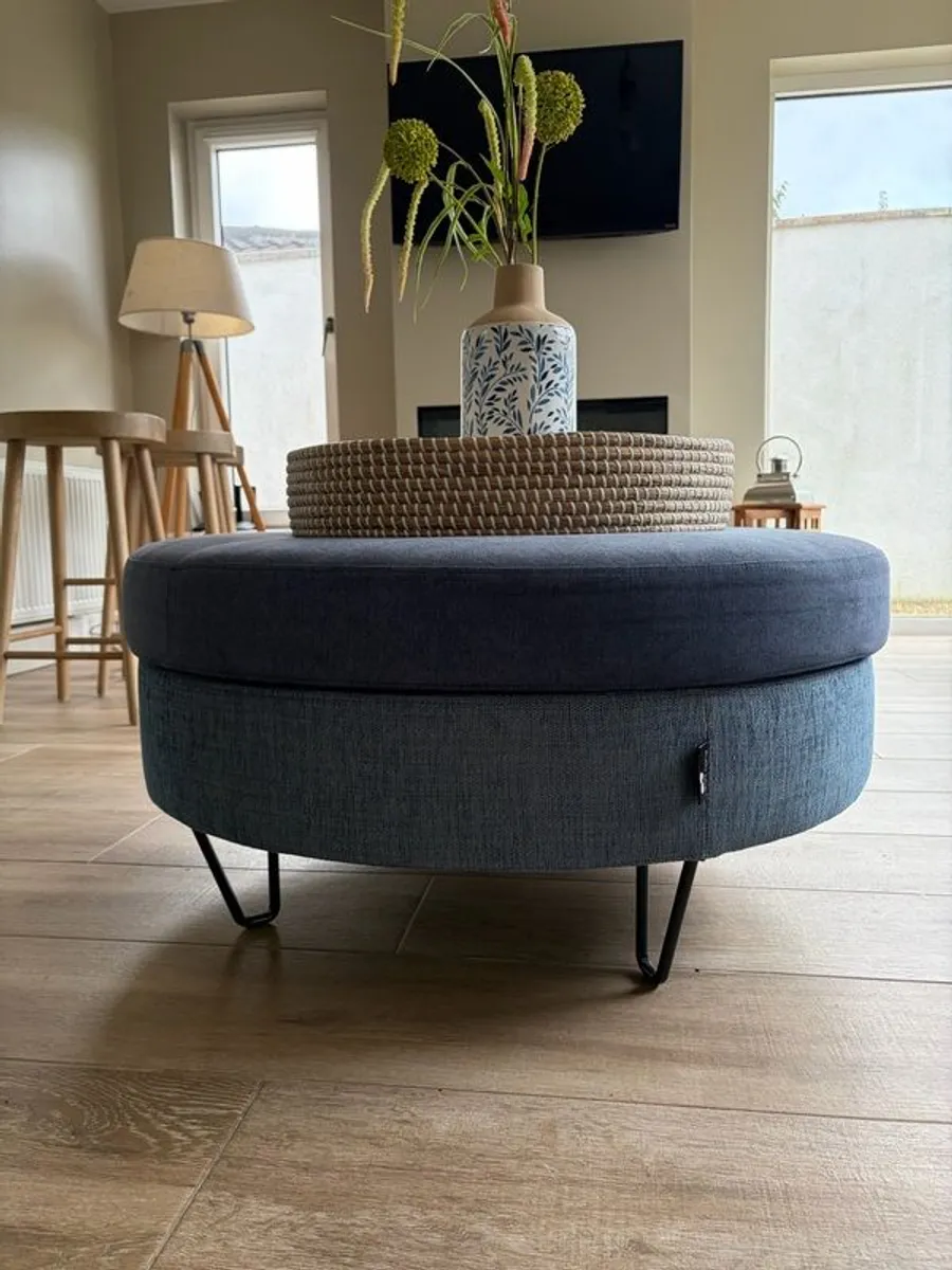 Large Round Blue Ottoman / Footstool with Storage  Stylish round ottoman with a dark denim-blue cushioned top, textured lighter blue base and black metal legs.  The top lifts off to reveal a handy storage space. Perfect as a footstool or styled with a tra - Image 1